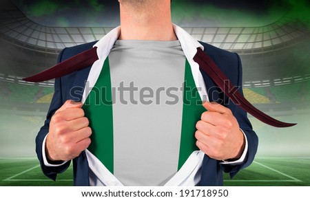 Businessman opening shirt to reveal nigeria flag against vast football stadium for world cup