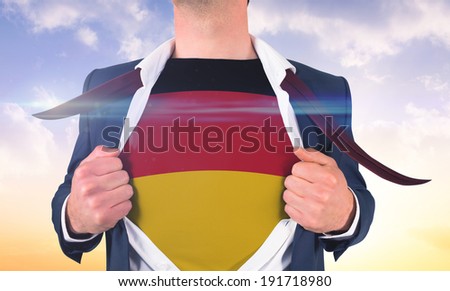 Businessman opening shirt to reveal germany flag against beautiful orange and blue sky