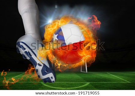 Football player kicking flaming chile flag ball against football pitch and goal under spotlights