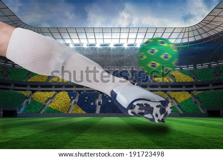Composite image of close up of football player kicking brasil ball against large football stadium with brasilian fans