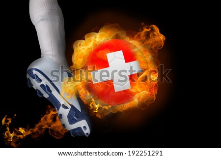 Football player kicking flaming switzerland ball against black