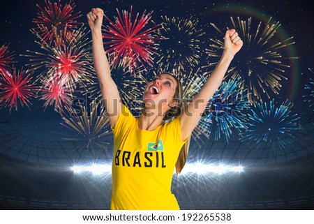 Pretty football fan in brasil t-shirt against fireworks exploding over football stadium