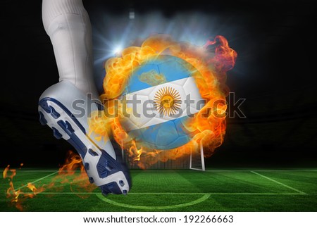 Football player kicking flaming argentina flag ball against football pitch and goal under spotlights