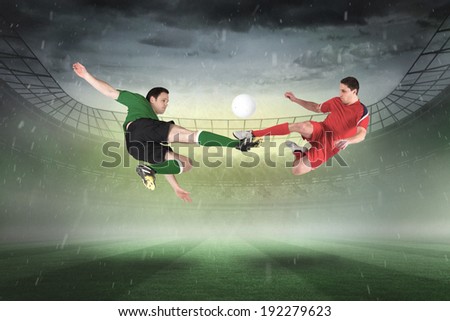 Football players tackling for the ball against misty football stadium under spotlights