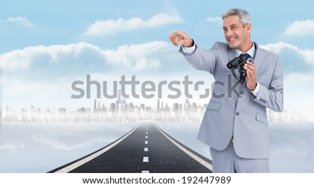 Businessman holding binoculars and pointing out something against open road background