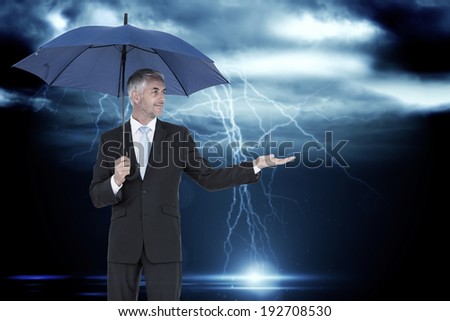Happy businessman holding umbrella against stormy dark sky with lightning bolts