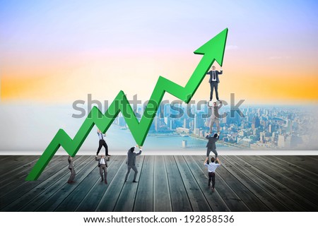 Business team holding up arrow against city projection on wall