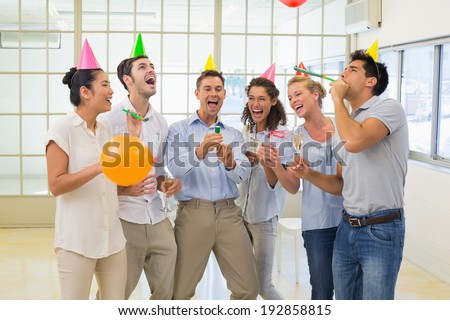 Casual business team celebrating with champagne and party poppers in the office