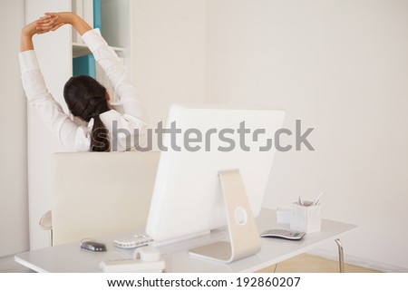 Casual businesswoman stretching at her desk in her office