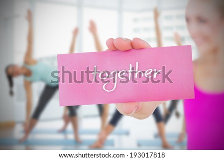 Fit blonde holding card saying together against fitness class in gym