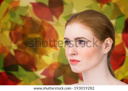 Beautiful redhead posing with hair tied against autumnal leaf pattern in warm tones