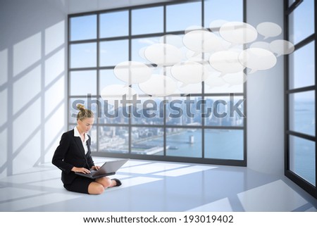 Businesswoman using laptop against room with large window showing city