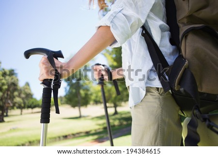 Fit woman walking with hiking pole in park on a sunny day
