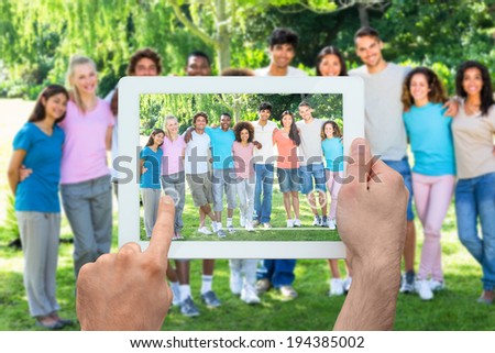 Hand holding tablet pc showing friends standing with arms around