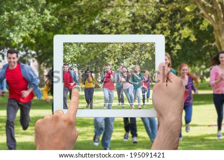 Hand holding tablet pc showing college students running in the park