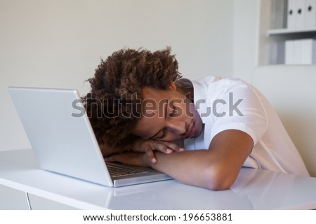 Casual businessman sleeping at his desk on his laptop in his office