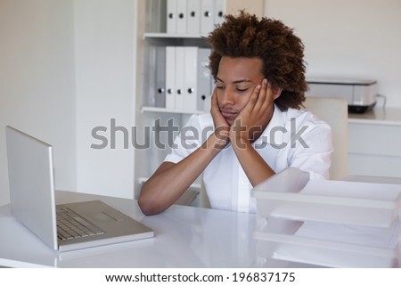 Casual businessman feeling exhausted at his desk in his office