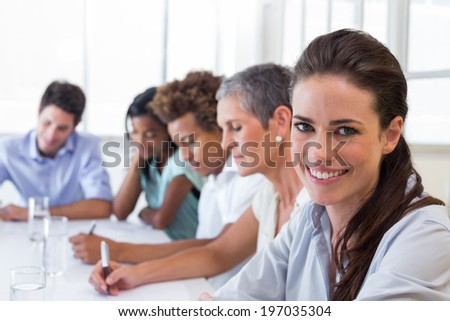 Businesswoman smiling into the camera at a business meeting with her coworkers