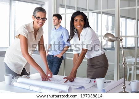 Smiling architects analyzing plans together in the office