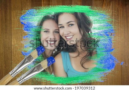 Composite image of friends smiling at camera with paintbrush dipped in blue against wooden surface with planks