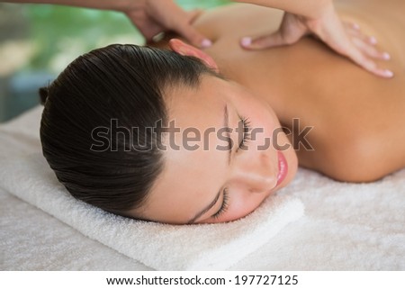 Brunette enjoying a peaceful massage with eyes closed at the health spa