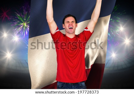 Cheering football fan in red against fireworks exploding over football stadium and france flag
