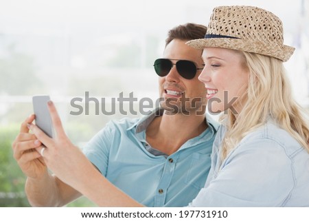 Cute couple sitting in cafe looking at smartphone on a sunny day in the city