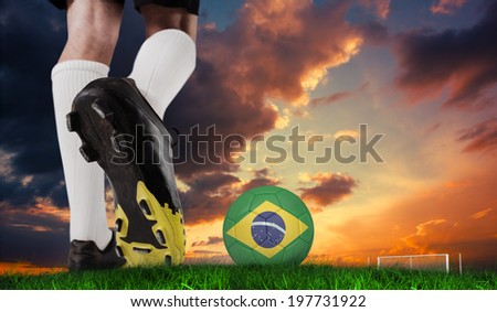 Composite image of football boot kicking brazil ball against green grass under dark blue and orange sky