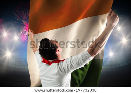 Excited football fan cheering against fireworks exploding over football stadium and ivory coast flag
