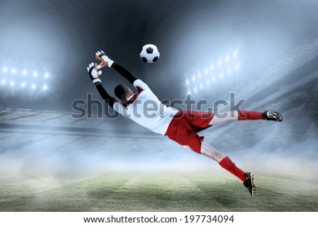 Fit goal keeper jumping up against football stadium