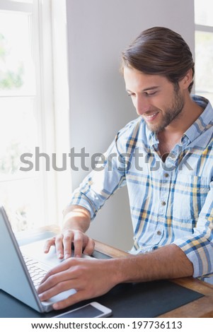 Handsome man sitting at table using laptop at home in the living room