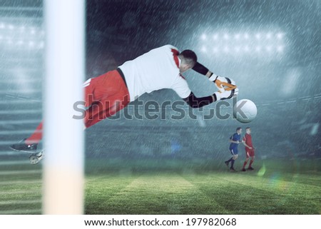 Fit goal keeper jumping up against large football stadium under blue sky