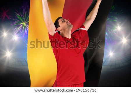 Excited football player cheering against fireworks exploding over football stadium and germanyflag
