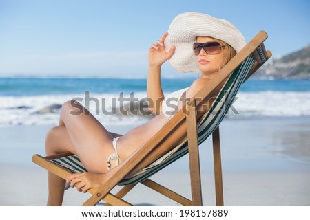 Pretty woman relaxing in deck chair on the beach on a sunny day