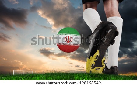 Composite image of football boot kicking iran ball against green grass under blue and orange sky