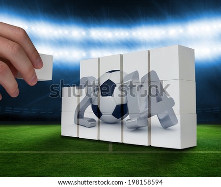 Hand building wall against football pitch under blue lights