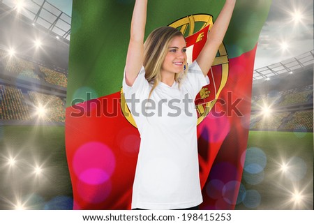 Pretty football fan in white cheering holding portugal flag against large football stadium with lights