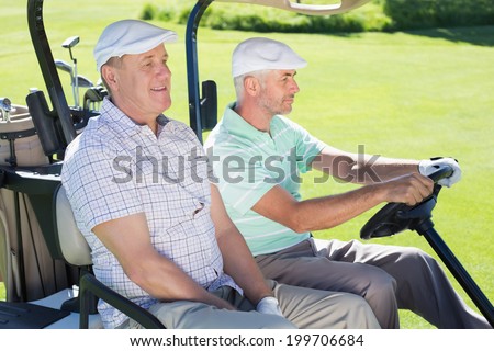 Golfing friends driving in their golf buggy on a sunny day at the golf course