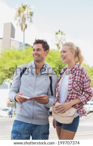 Young tourist couple consulting the guide book on a sunny day in the city