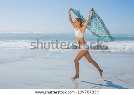 Gorgeous fit blonde running by the sea with scarf on a sunny day