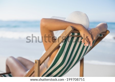 Slim woman relaxing in deck chair on the beach on a sunny day