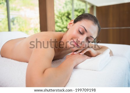 Beautiful brunette lying on massage table with eyes closed in the health spa