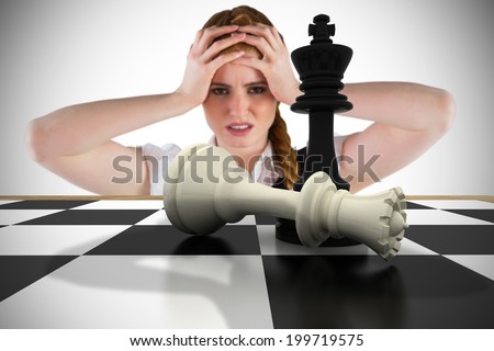 Stressed businesswoman with hands on head with chessboard against white background with vignette