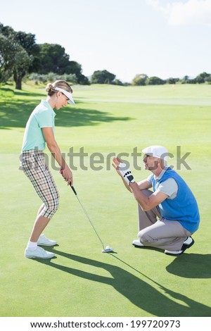 Man coaching his partner on the putting green on a sunny day at the golf course