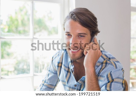 Smiling casual man talking on smartphone at home in the living room