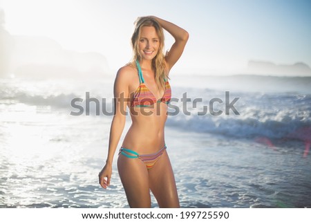 Happy blonde standing in the sea posing in bikini on a sunny day