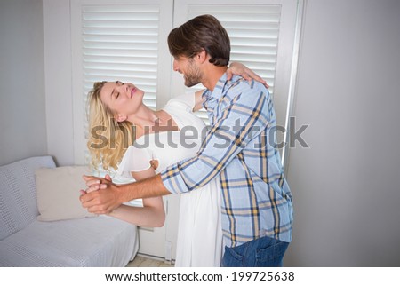 Cute young couple dancing together at home in the living room