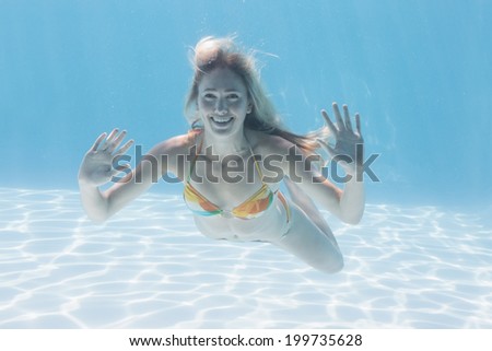 Cute blonde smiling at camera underwater in the swimming pool on her holidays