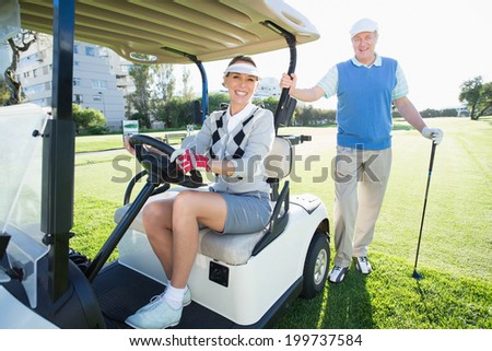 Happy golfing couple setting out for the day on buggy on a sunny day at the golf course