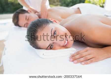Attractive couple enjoying couples massage poolside outside at the spa